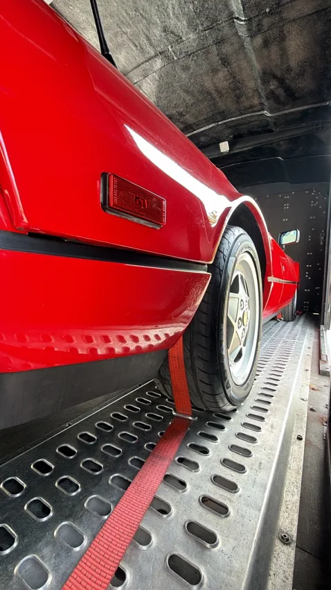 Détail d’une Ferrari rouge sur les rails de la remorque
