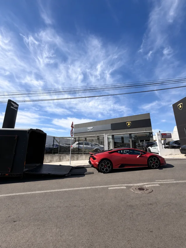 Lamborghini rouge à côté de la remorque fermée