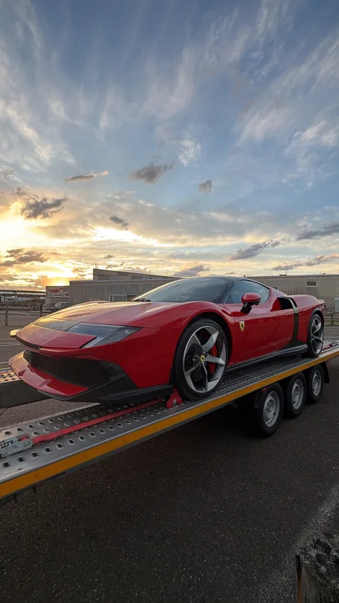 Ferrari rouge sur une remorque ouverte au coucher du soleil