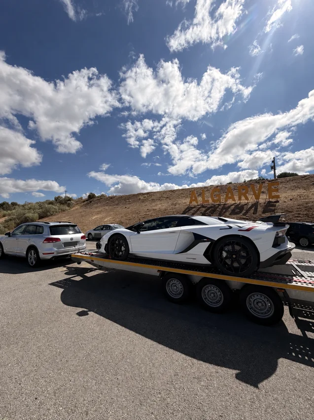 Lamborghini blanche sur une remorque devant le panneau Algarve